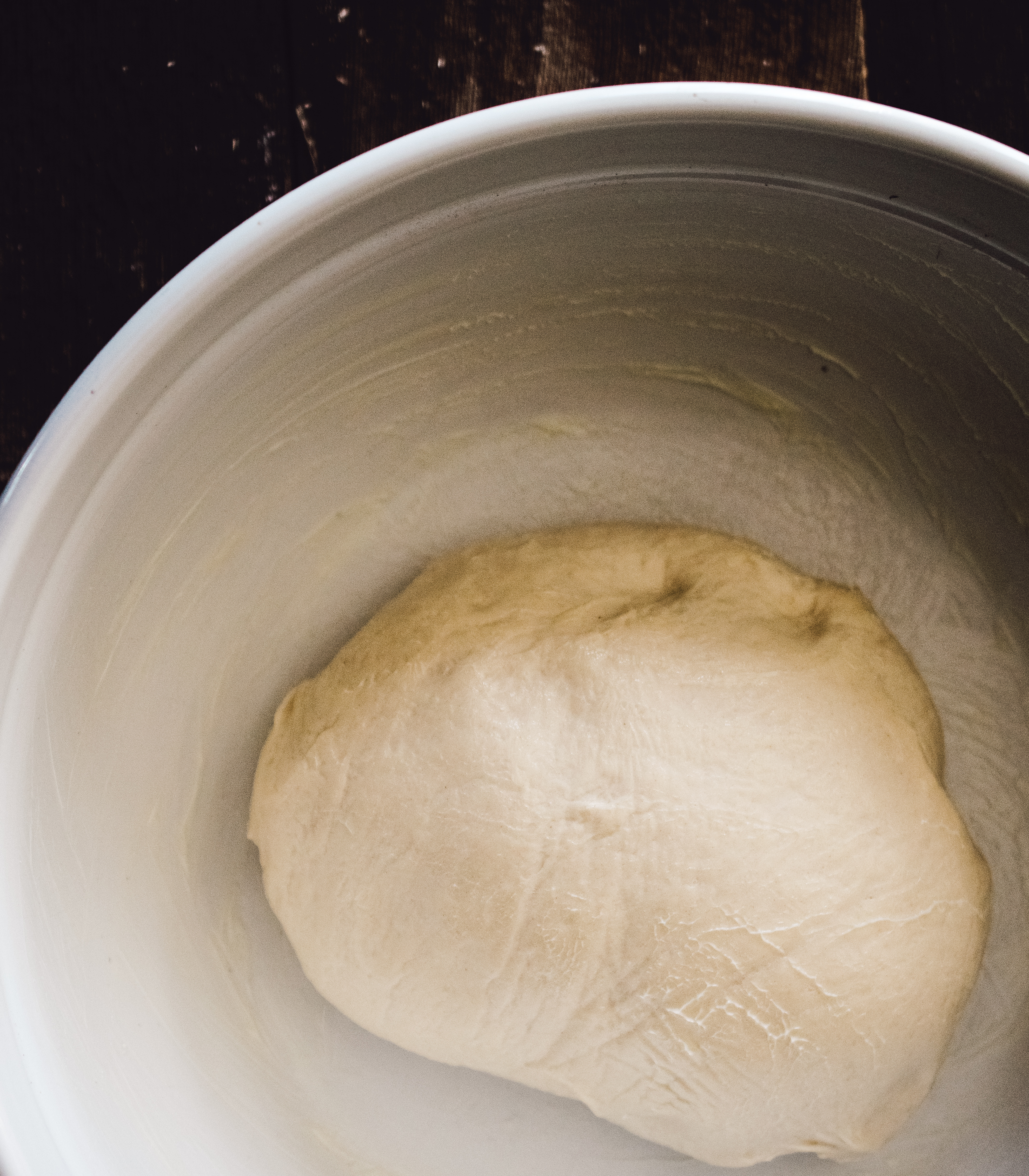 Ball of homemade white bread dough after kneading, showing desired texture, sitting in a greased bowl ready to begin first rise