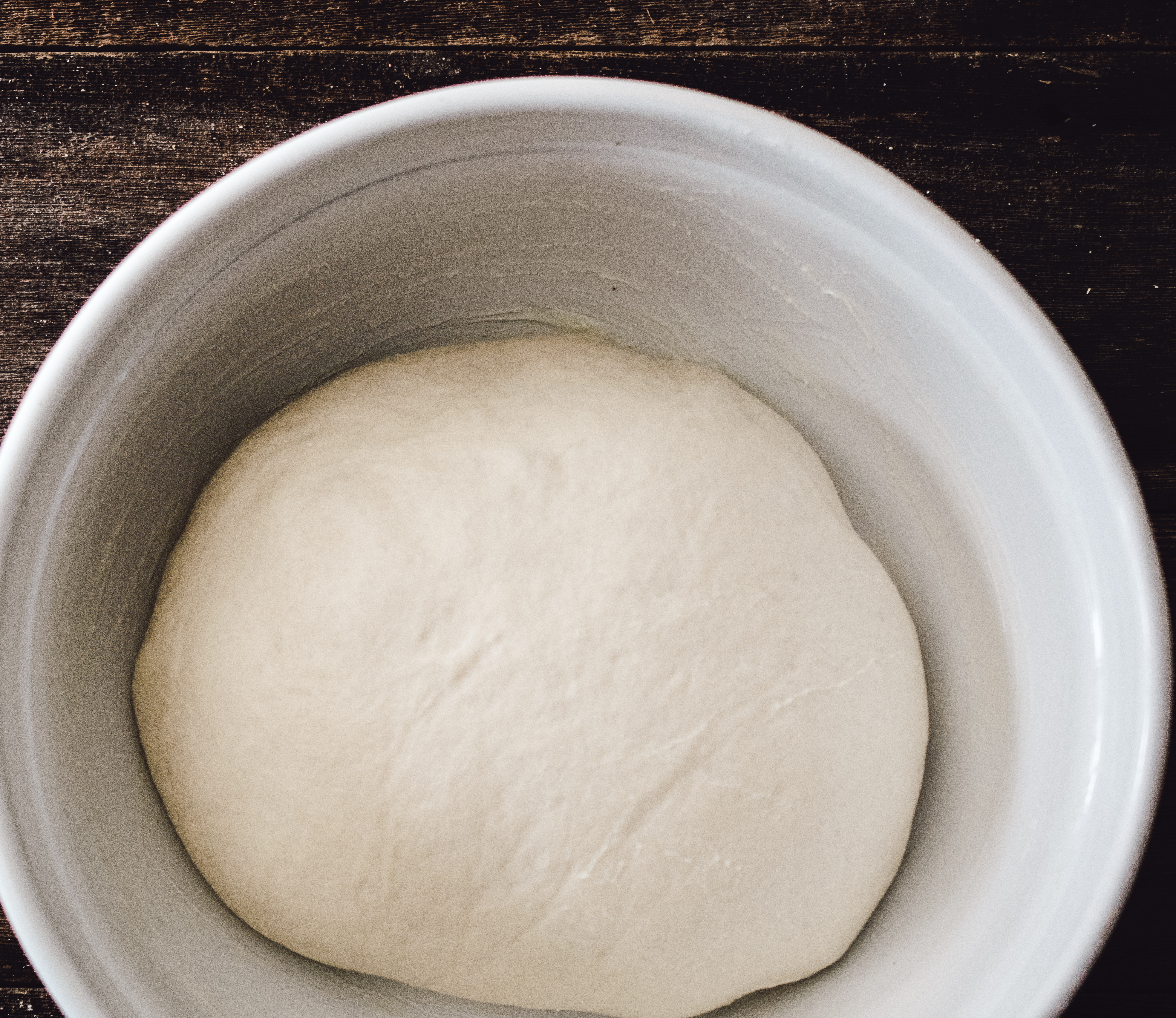 white bread dough in greased bowl, doubled in size after first rise