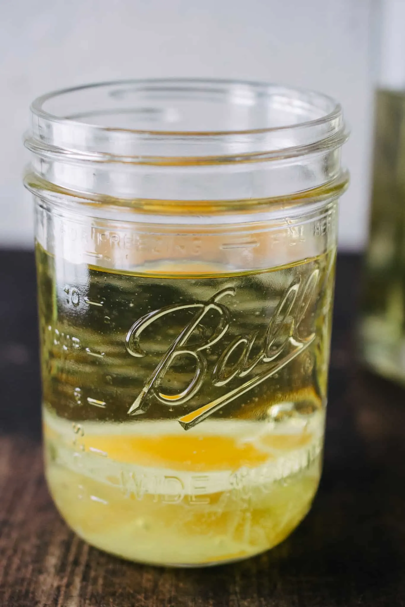 mason jar with raw egg, lemon juice and oil on wooden surface to be made into mayonnaise