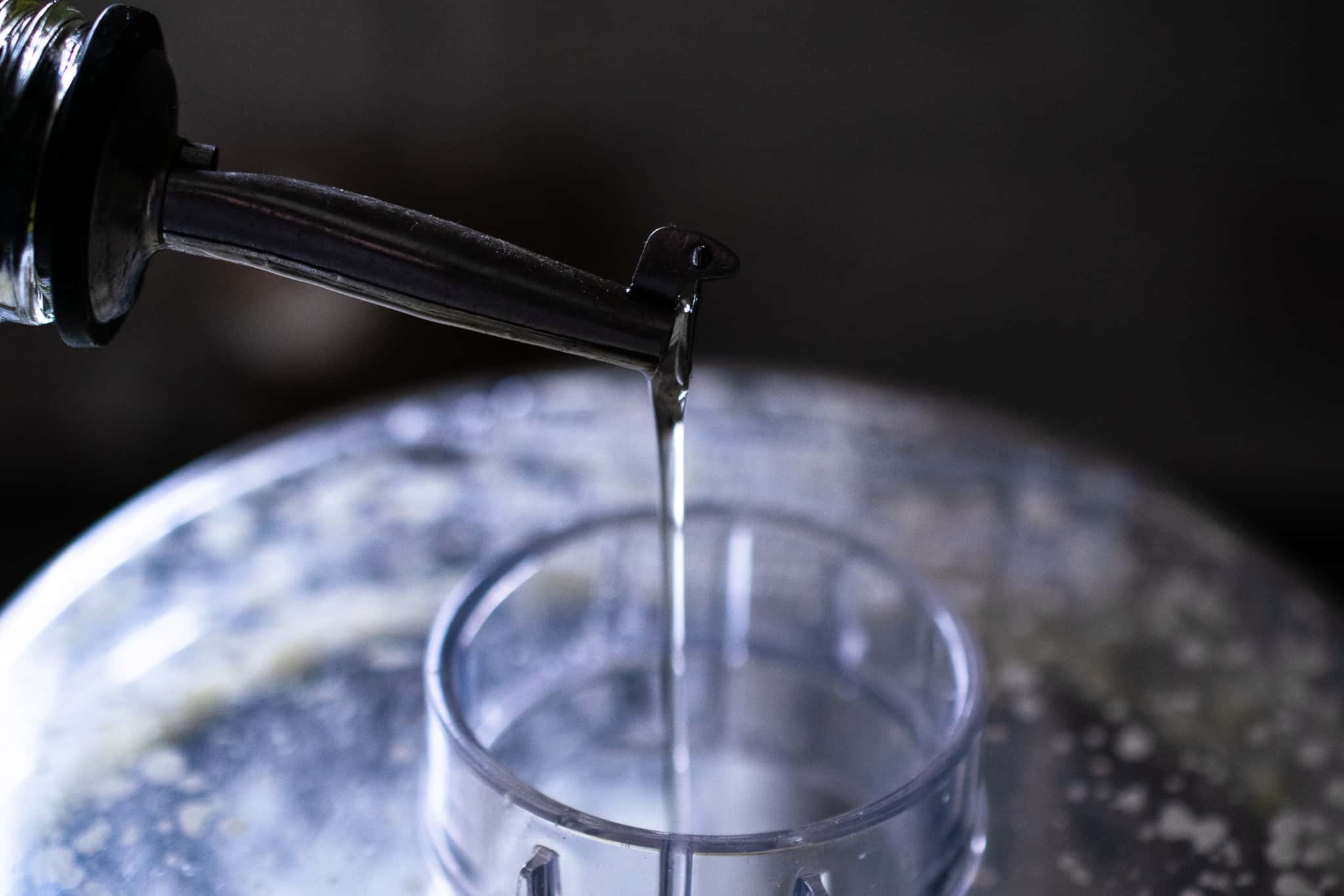 thin stream of oil being poured into a food processor for making mayonnaise