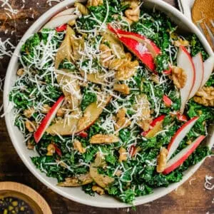 Bowl of chopped kale, sliced pears, walnuts and shredded Parmensan cheese.