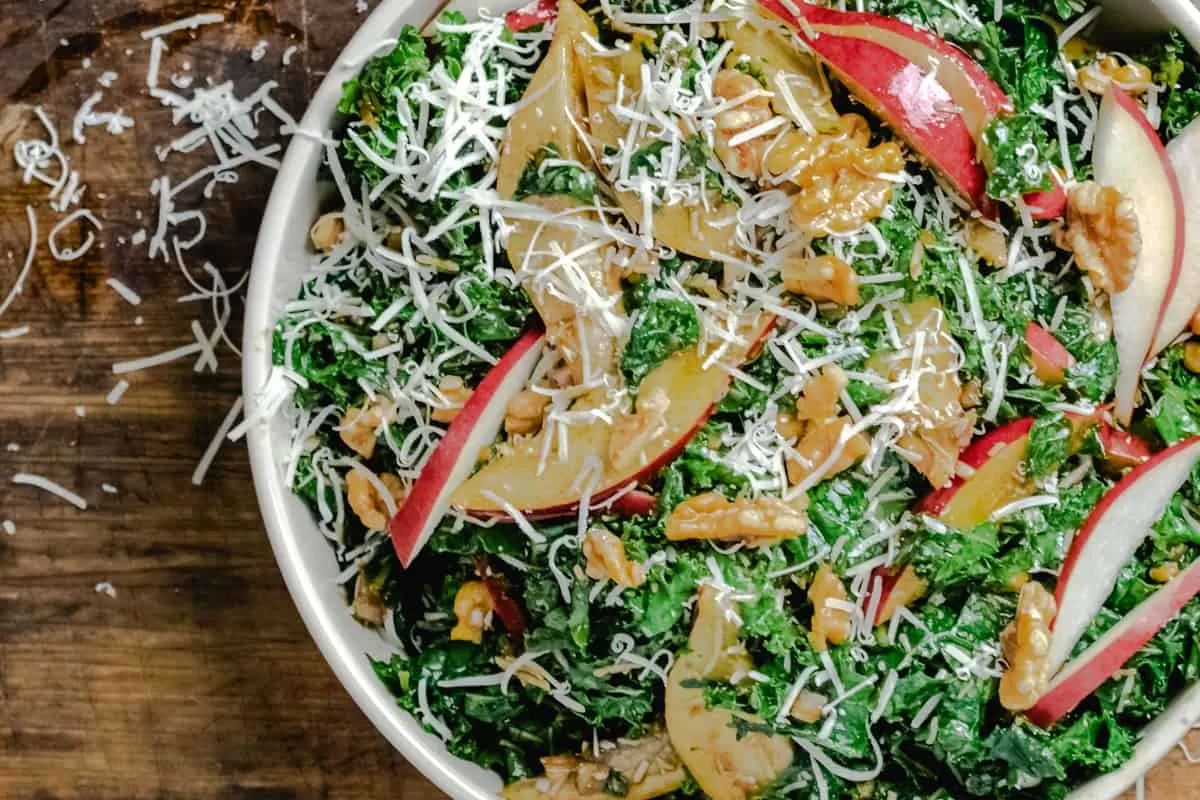 Bowl of tossed greens with red pears and walnuts. 