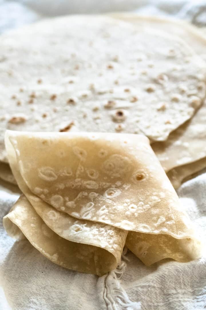 homemade flour tortilla folded into quarters to show flexibility on white cloth