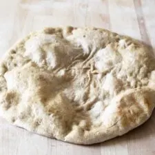 homemade wheat pizza crust on wooden cutting board