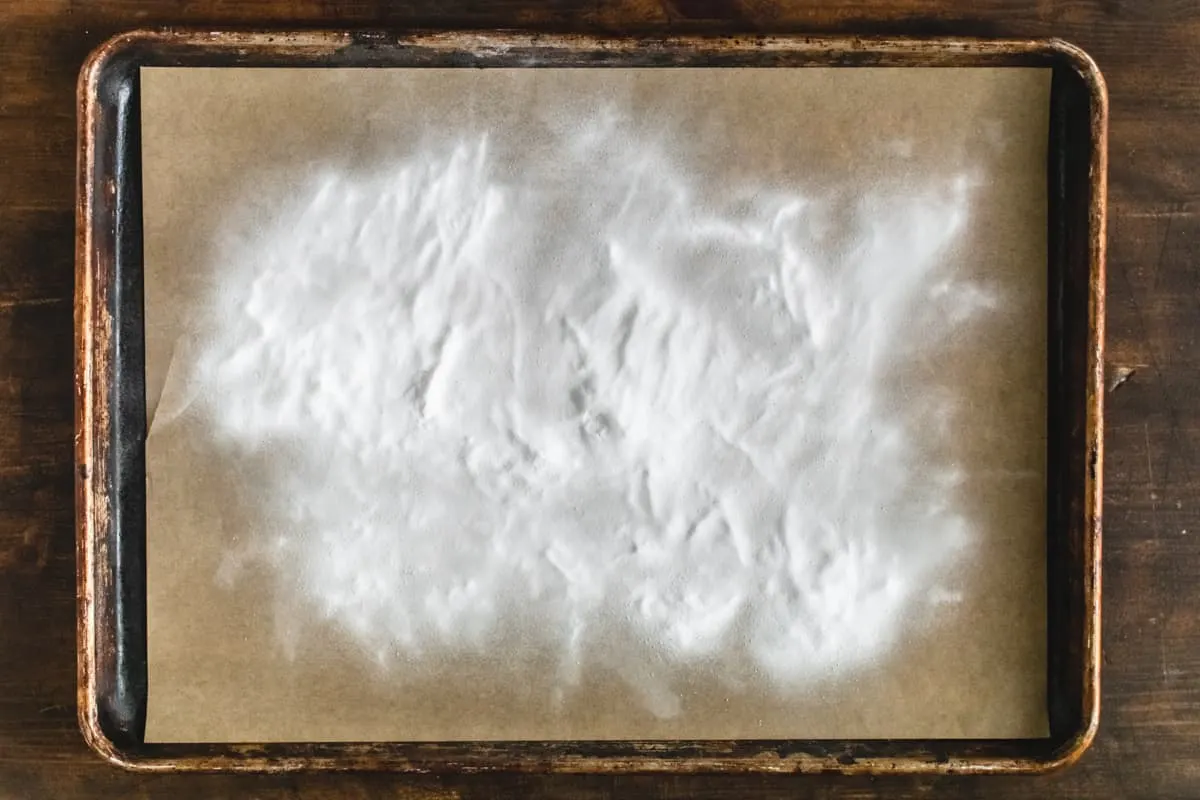Baking soda sprinkled on parchment paper on a baking sheet.