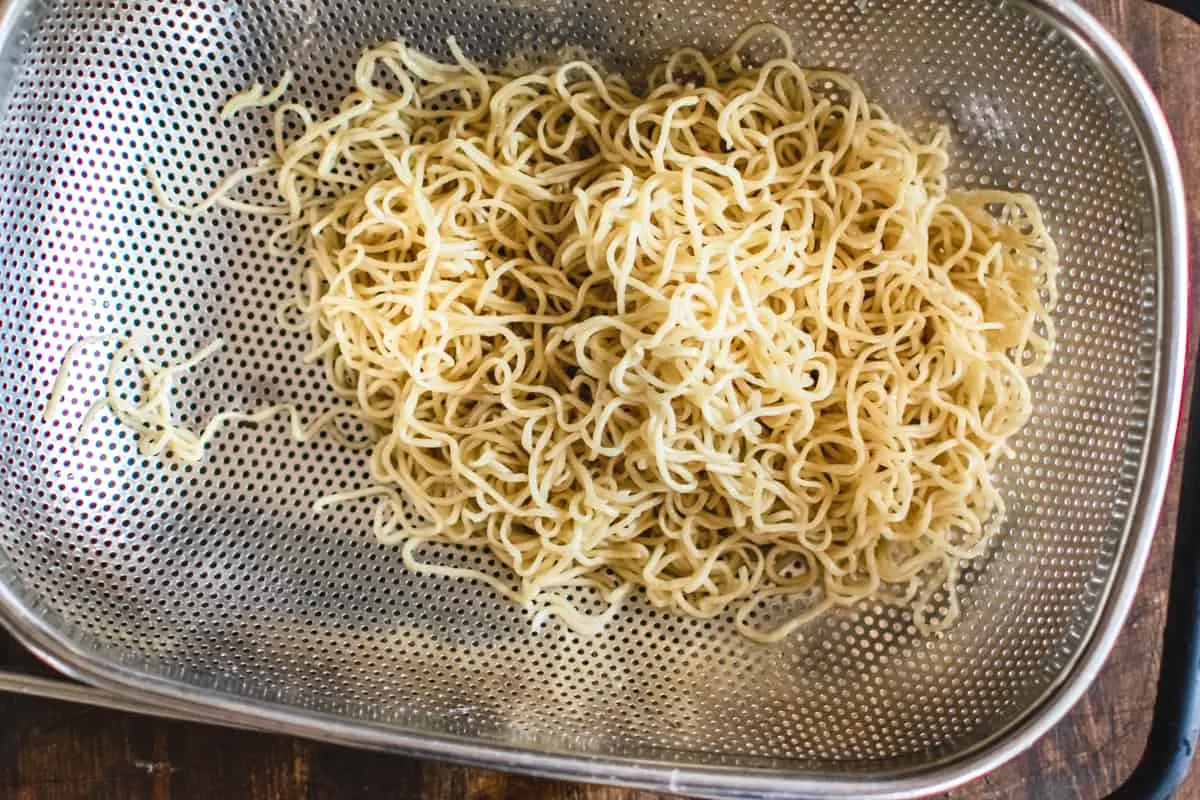 Cooked ramen noodles in a metal strainer.