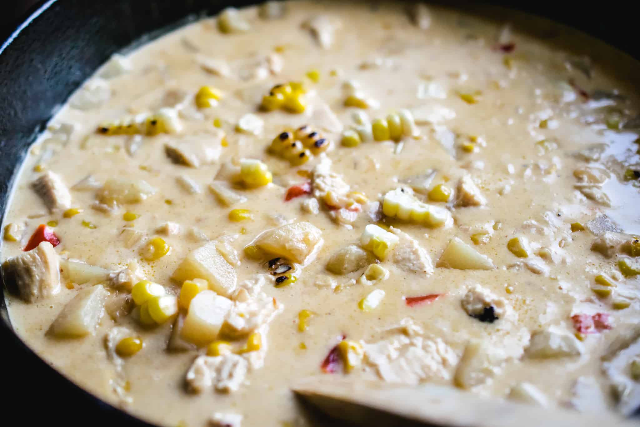 cast iron pot of corn chowder with diced potatoes and red bell pepper 