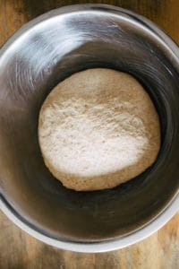 bread dough in greased metal bowl beginning first rise
