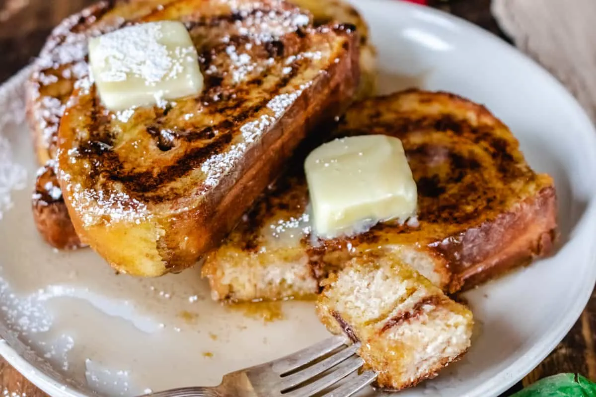 Plate of French toast with bite taken out by a napkin. 