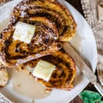 Three pieces of French toast swirled with brown sugar and cinnamon swirl on a plate with butter and syrup.