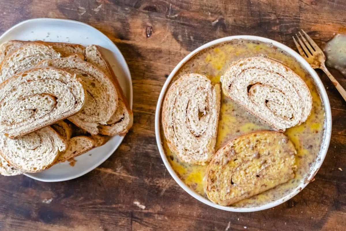 French toast being dipped into whisked eggs with cinnamon.