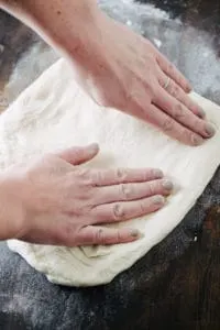 hands stretching pizza dough