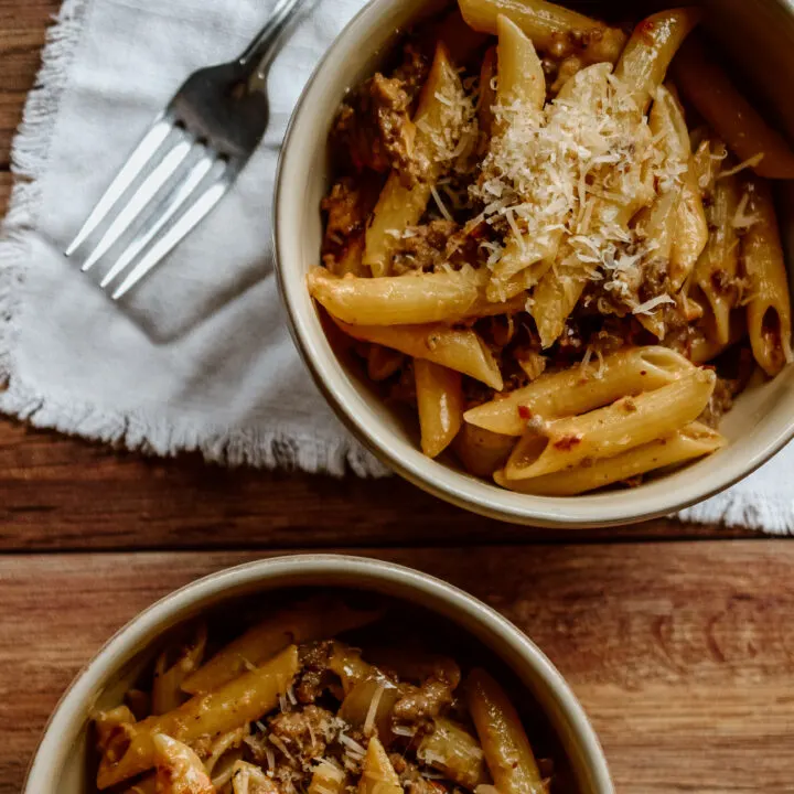 Penne shaped pasta with Parmesan cheese and red sauce in two bowls.