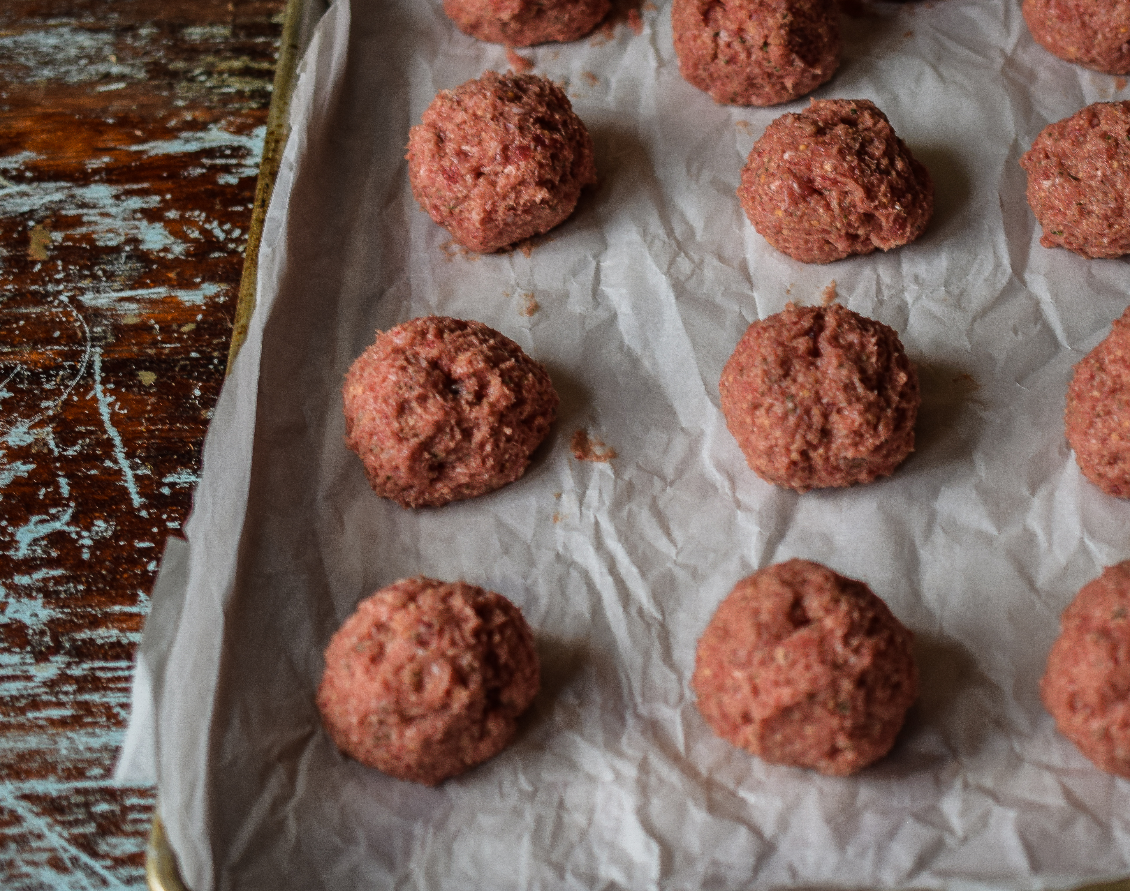 Balls of ground beef shaped into balls on a baking sheet.