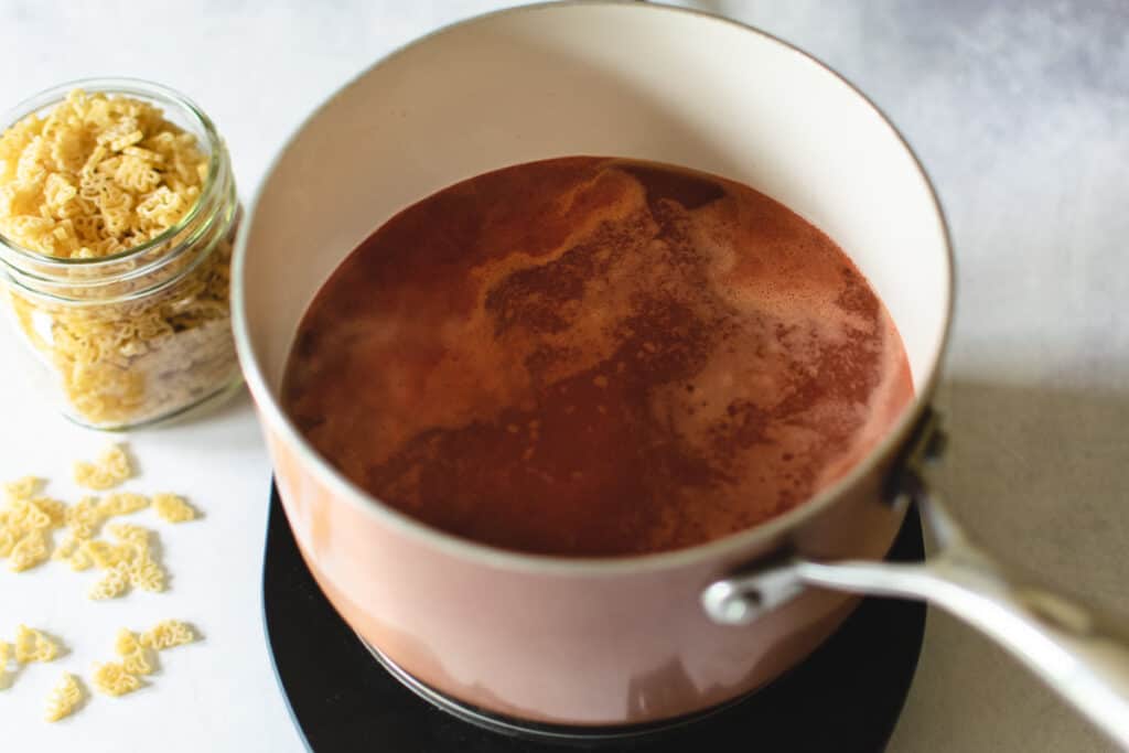 pot of tomato puree and chicken stock being brought to a boil