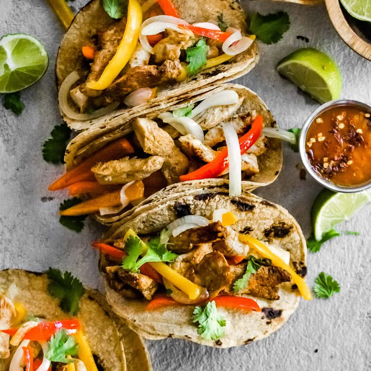 An arrangement of fajita tacos with cilantro and lime.