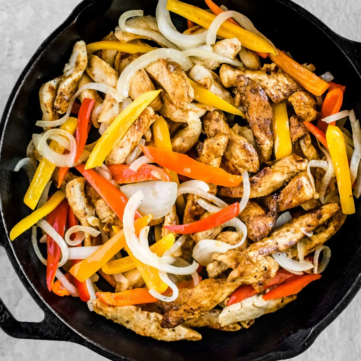 Chicken fajitas with bell peppers in a skillet.