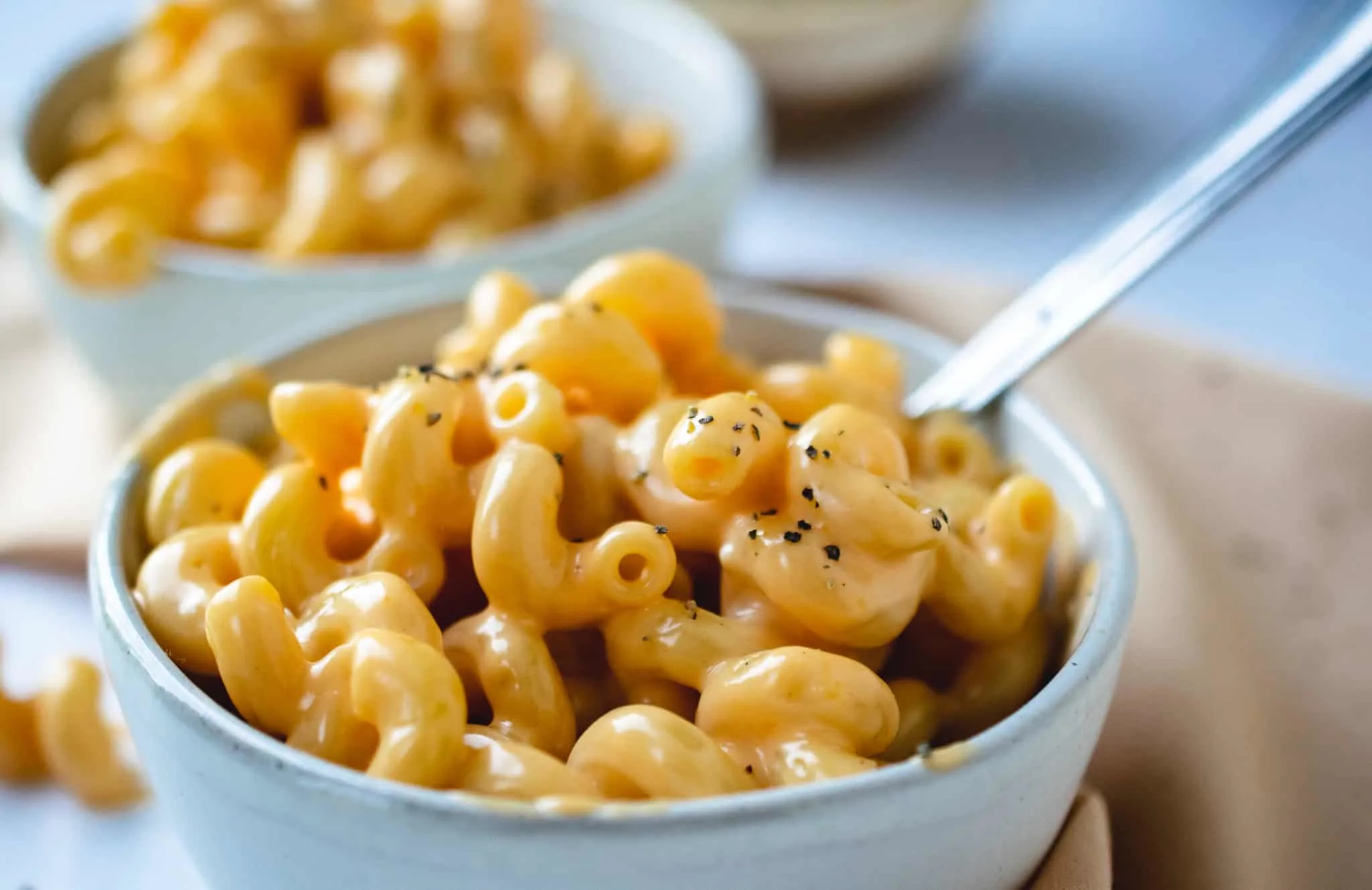 white stone bowl with macaroni and cheese with black pepper and fork