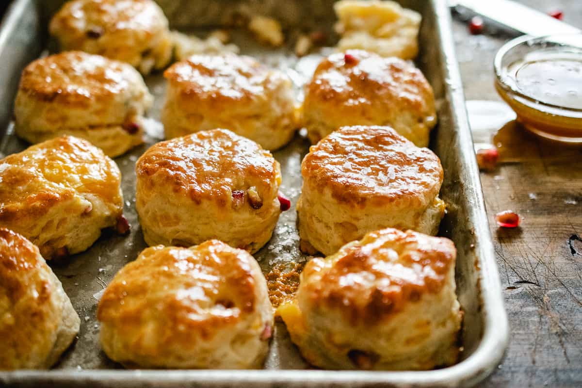 Cheesy biscuits with pomegranate seeds on a baking sheet.