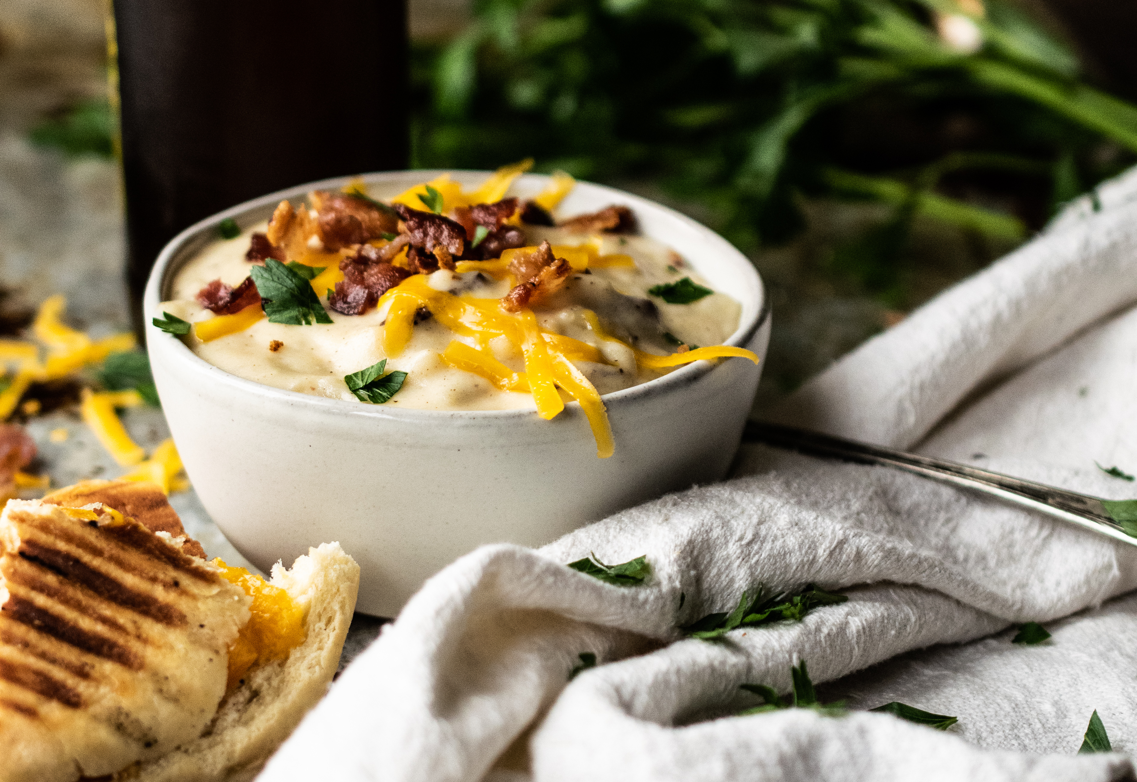 Bowl of soup with cheese, bacon and a bottle of cold beer.