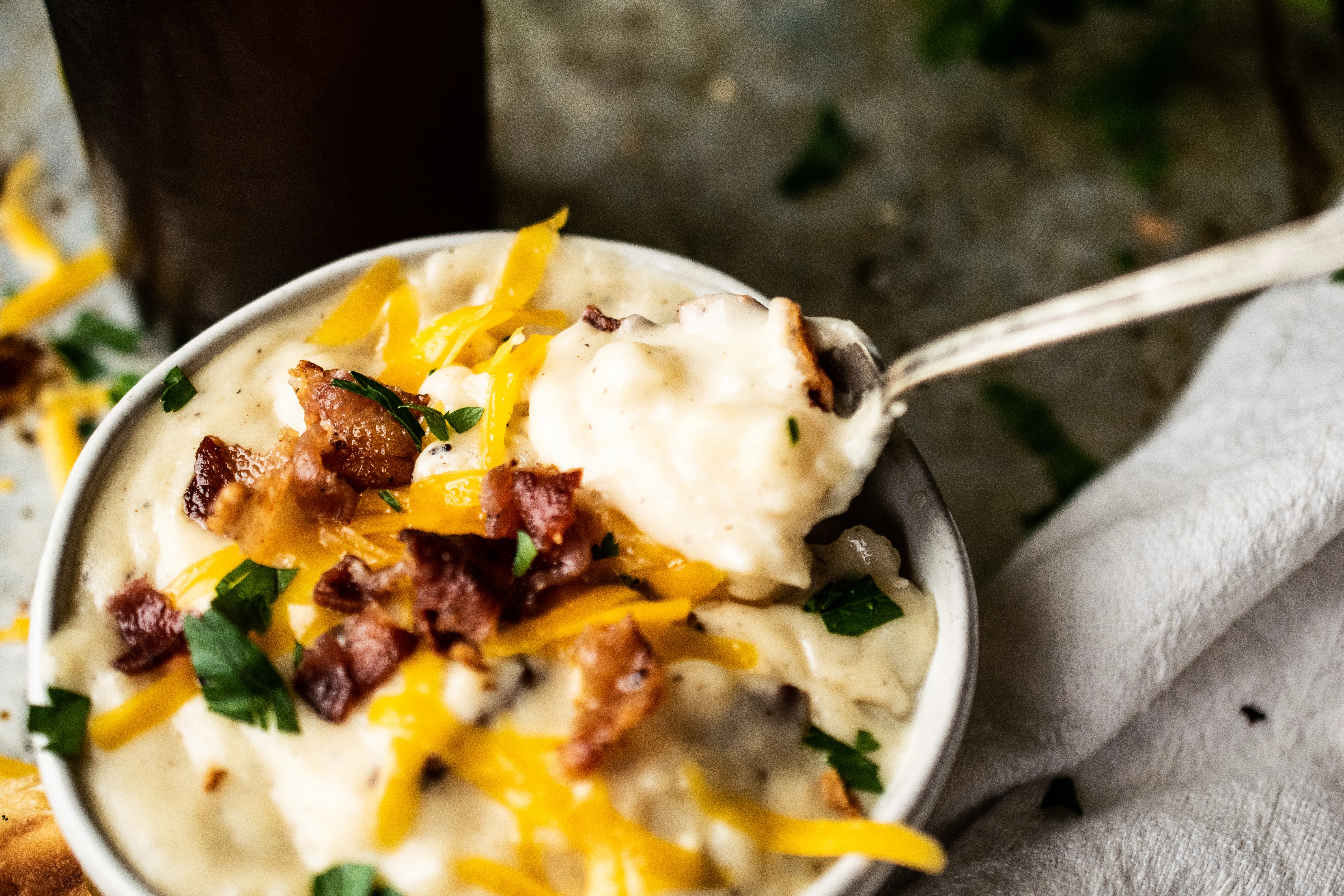 A bowl of creamy potato soup with cheese and bacon.