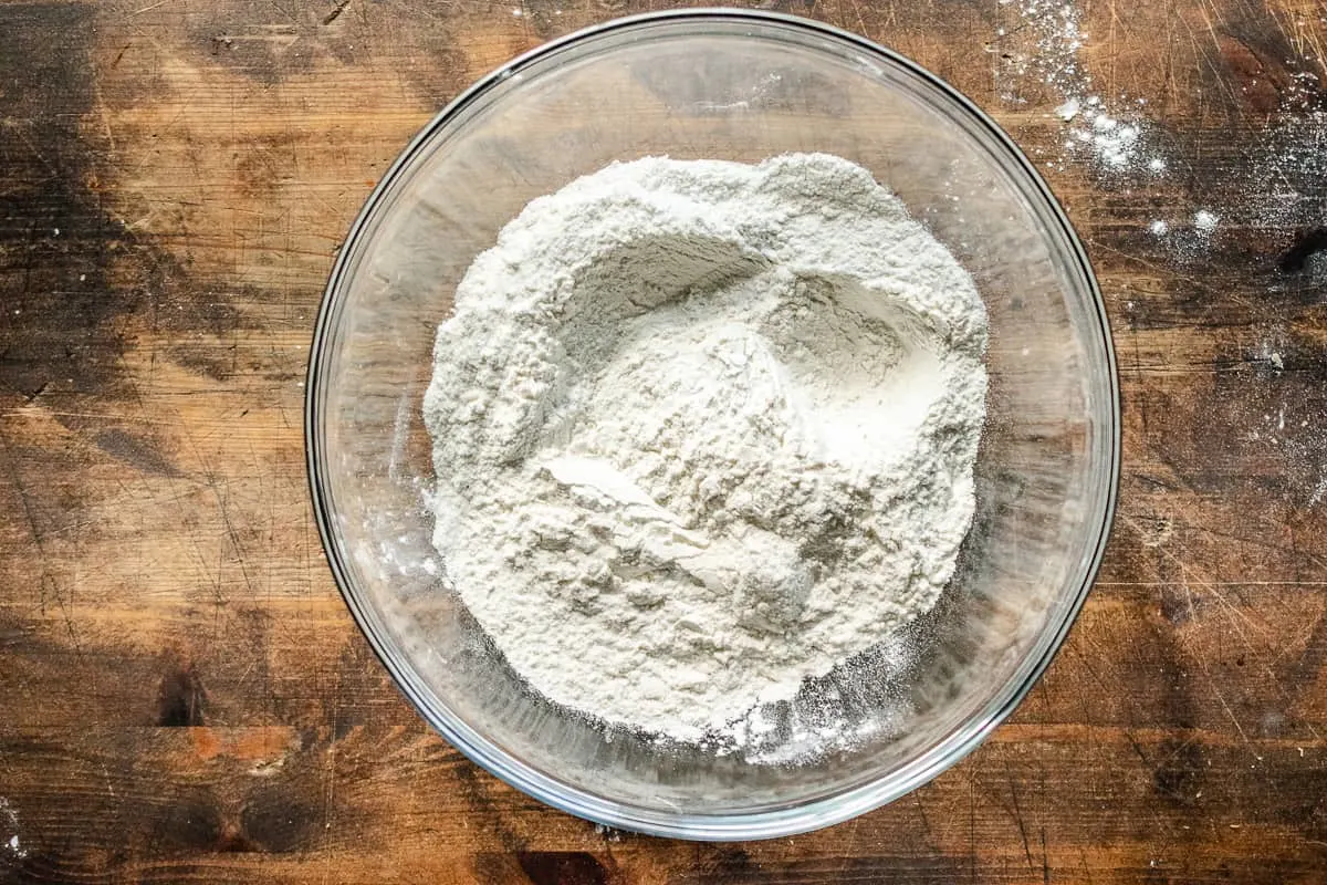 Flour, baking powder, sugar, and salt mixed in a glass bowl.