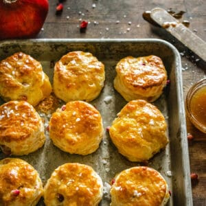 Cheddar and Pomegranate holiday biscuits drizzled with honey butter on a baking sheet.