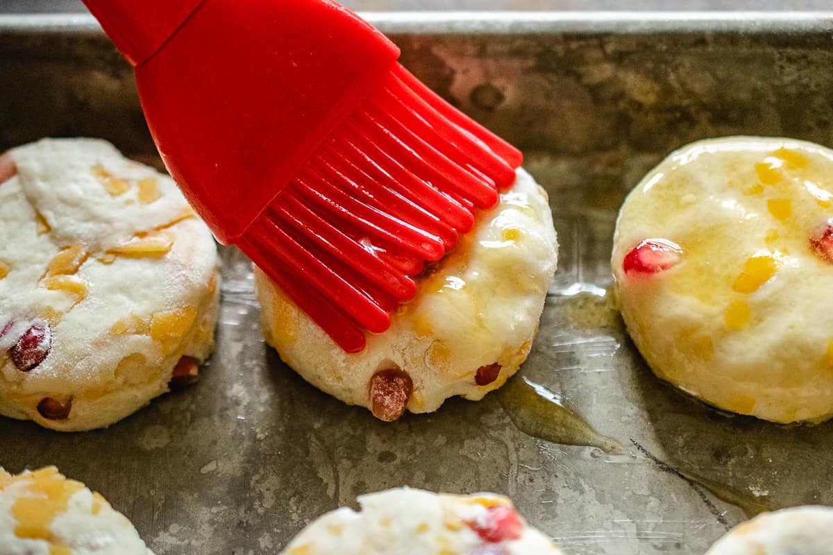 Brushing honey butter on cheddar pomegranate holiday biscuits.