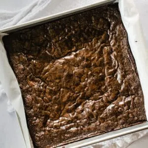 freshly baked brownies with shiny tops in a square pan