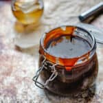 Gasket and hinge jar filled with barbecue sauce with honey on a whisk and glass of bourbon.