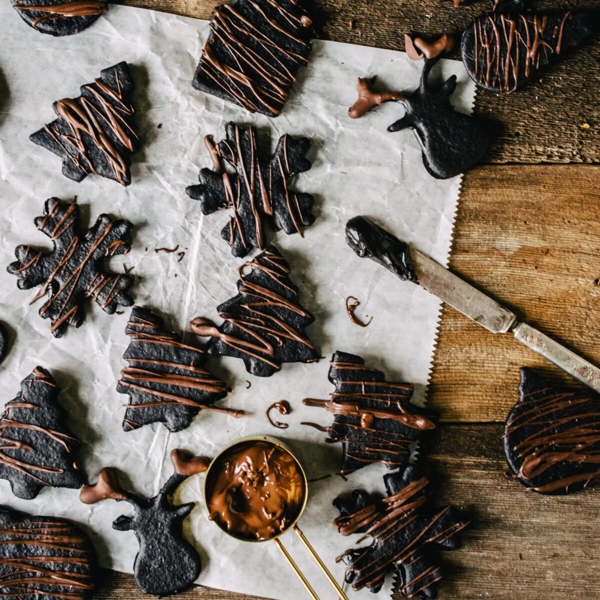 Chocolate holiday shaped cookies on wax paper.