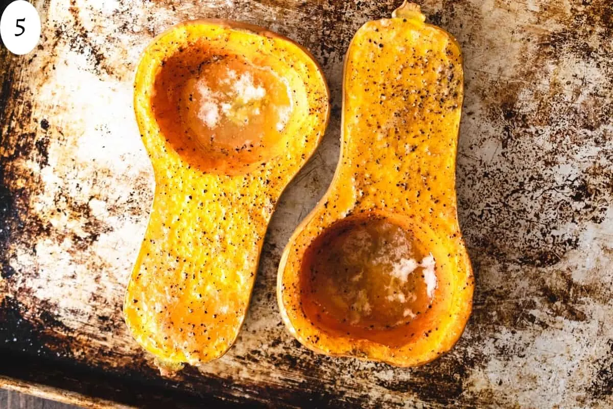 Two roasted butternut squash halves on an aluminum baking sheet.