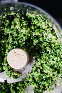 food processor with processed greens and pine nuts and cheese