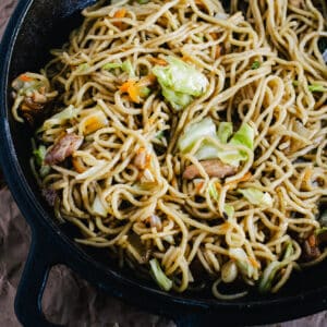 Stir fried noodles with cabbage, onion and carrots in a cast iron skillet.