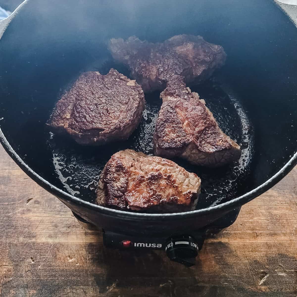 Large pieces of beef being seared in a pot. 