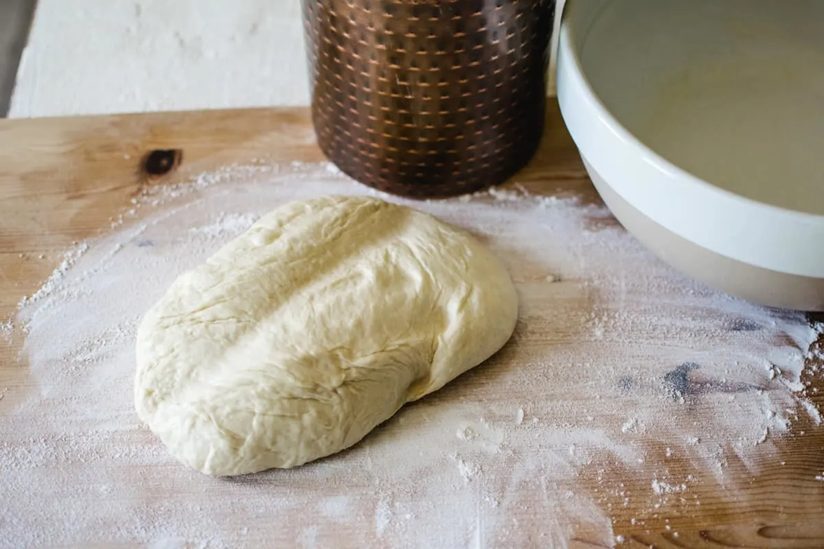 hamburger bun dough on a floured wooden surface