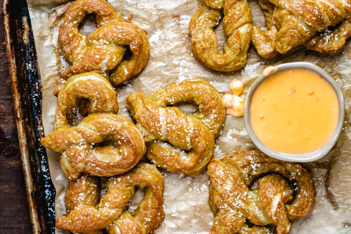 Beer cheese with soft pretzels on a baking sheet.