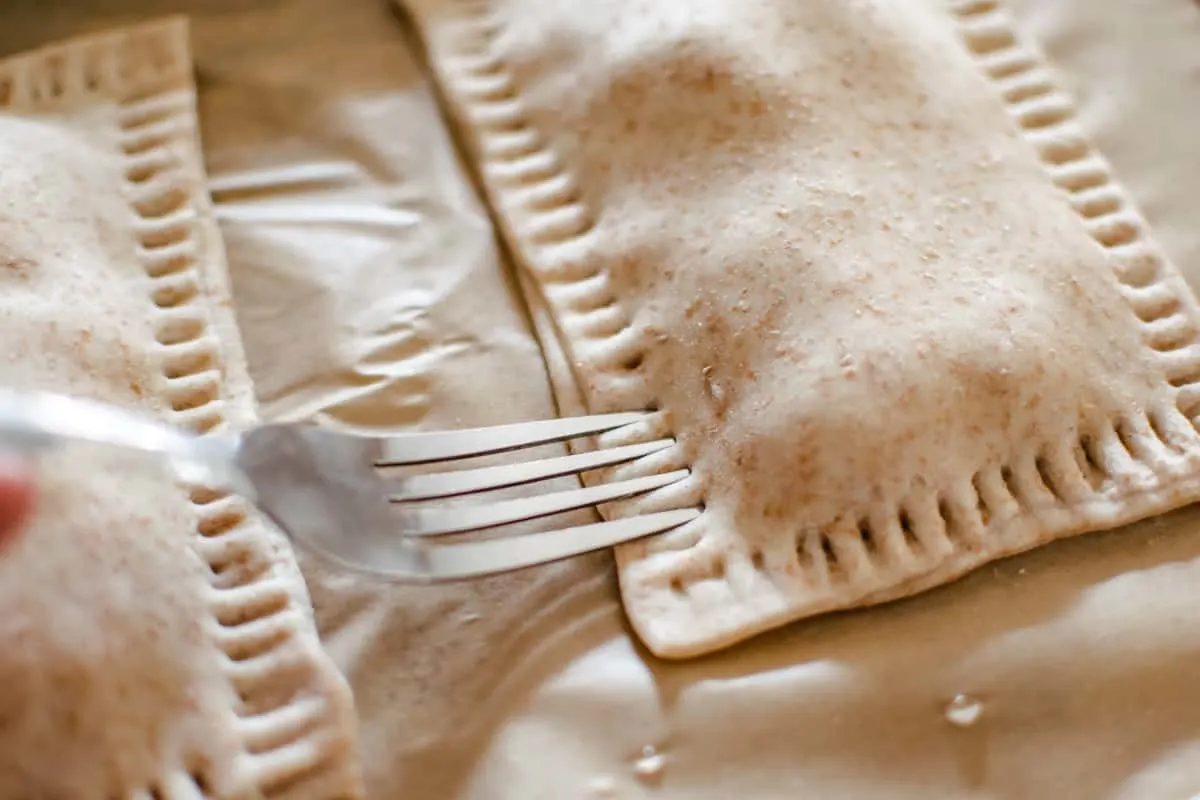 Uncooked hot pockets being pressed with the tines of a fork to seal the dough. 