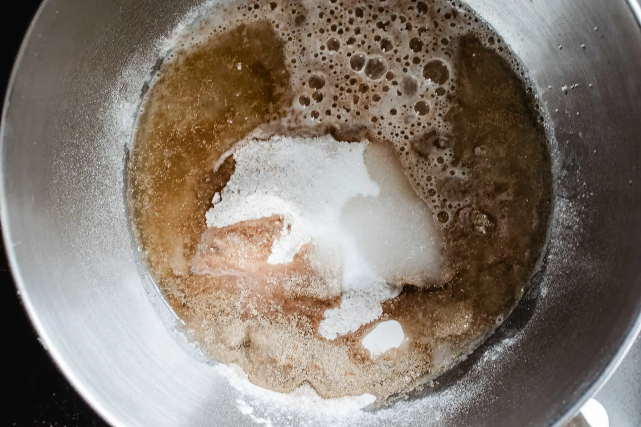 metal mixer bowl with whole wheat bread ingredients unmixed