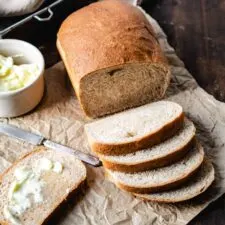 loaf of whole wheat bread sliced on parchment paper