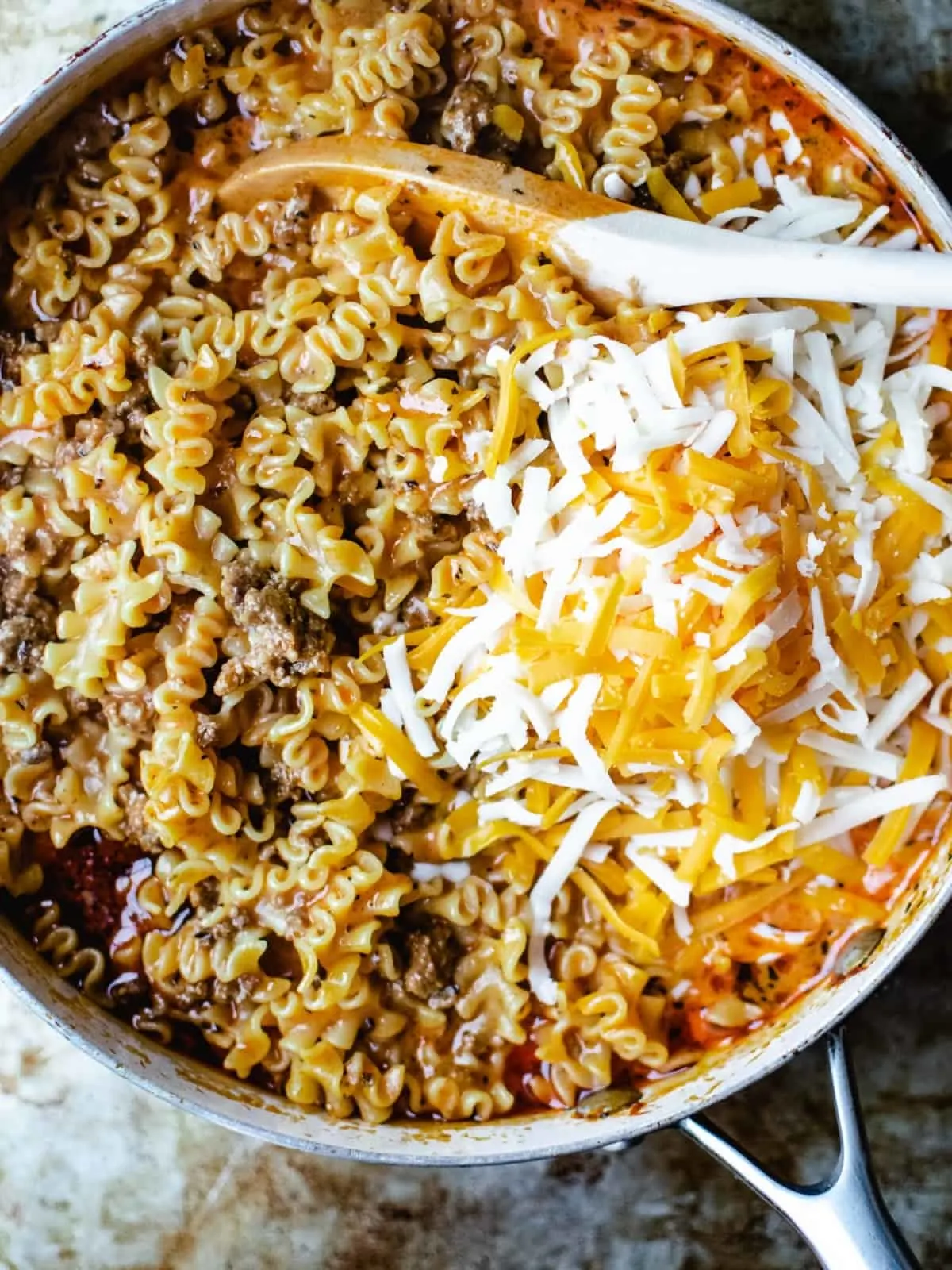 Shredded cheese in a tomato sauce with lasagna shaped pasta and hamburger.