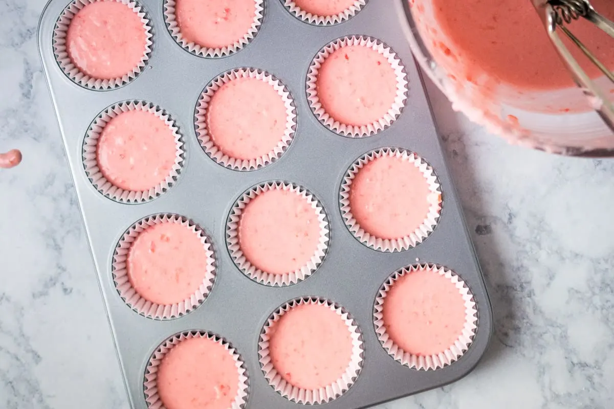 Cherry cupcake batter spooned into a cupcake pan.