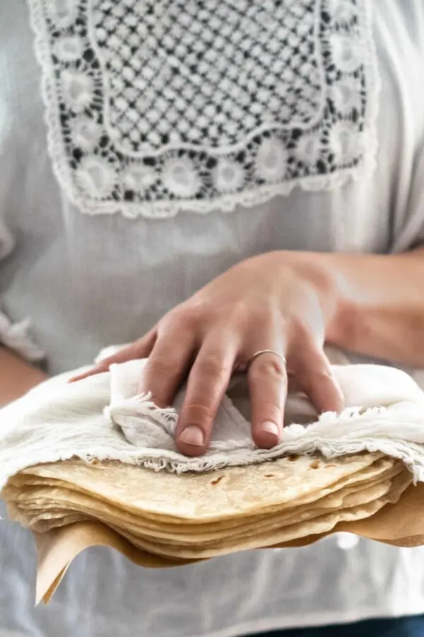 woman holding a stack of homemade soft flour tortillas