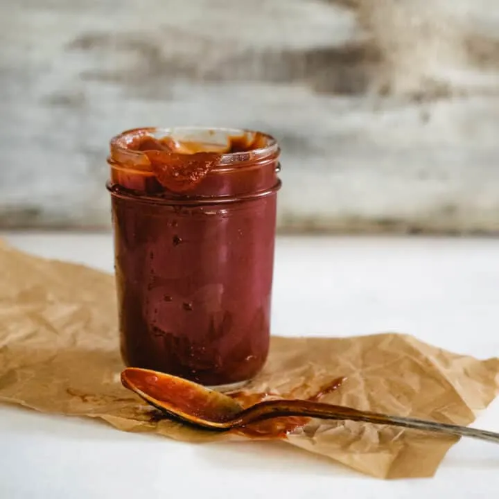 mason jar of homemade ketchup with antique spoon and distressed wooden backdrop