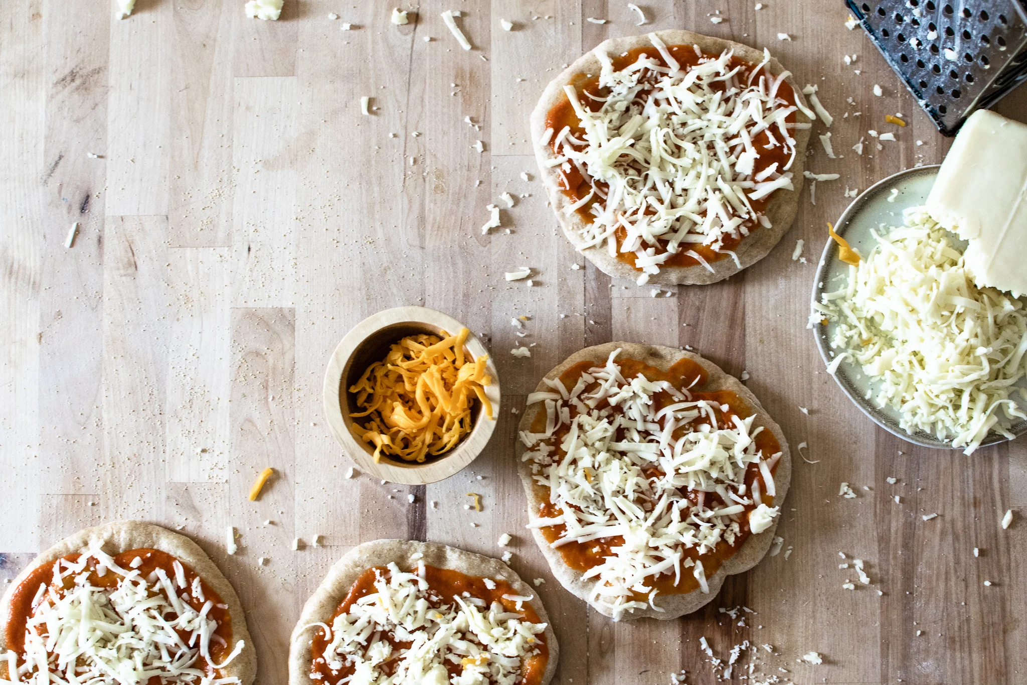 several personal size homemade frozen pizzas to be put into freezer for later with cheese topping