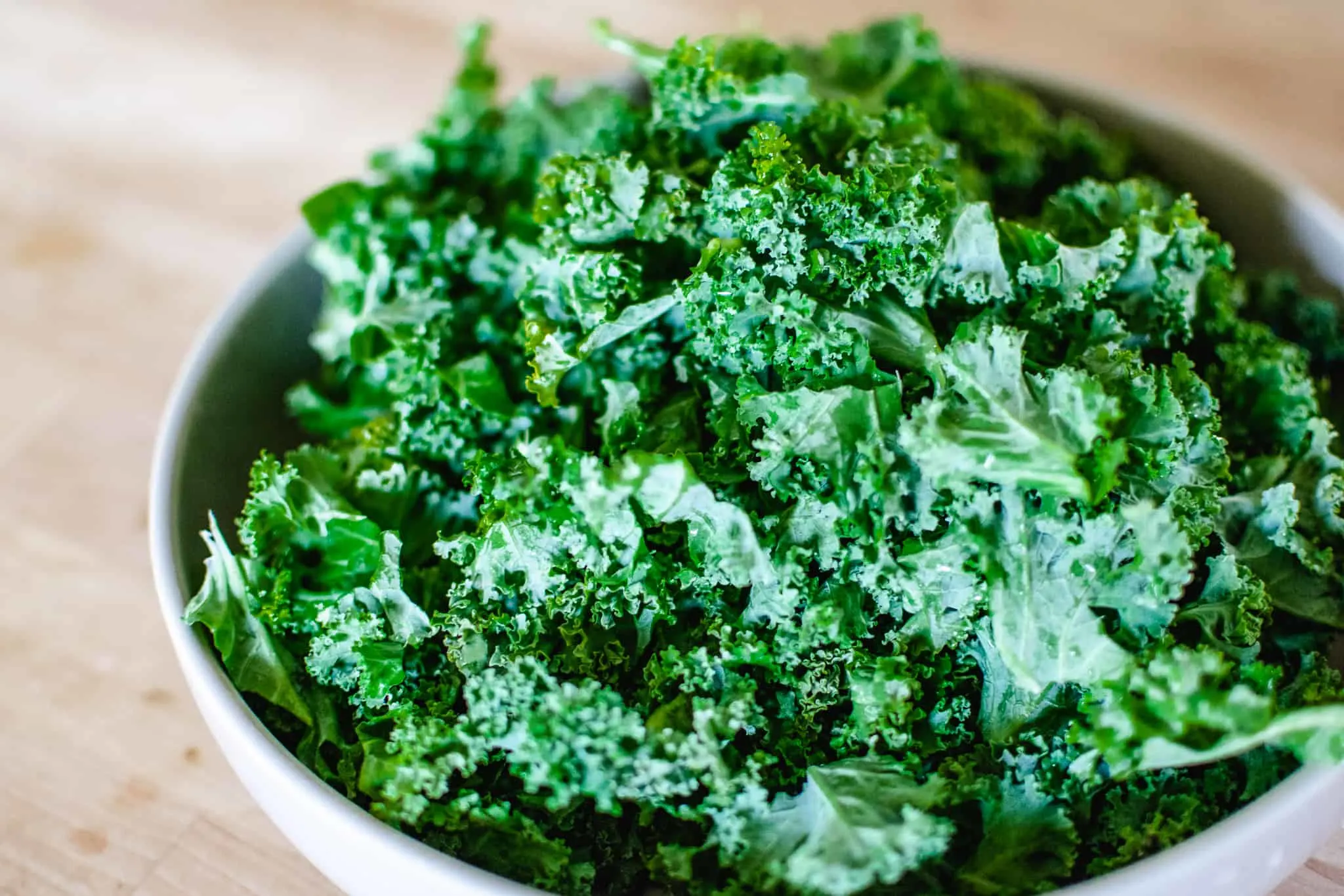 large ceramic bowl filled with chopped, raw kale for cooking into a pasta dish