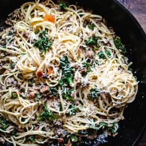 skillet of spicy sausage and kale linguine tossed with wine cream sauce and Parmesan cheese