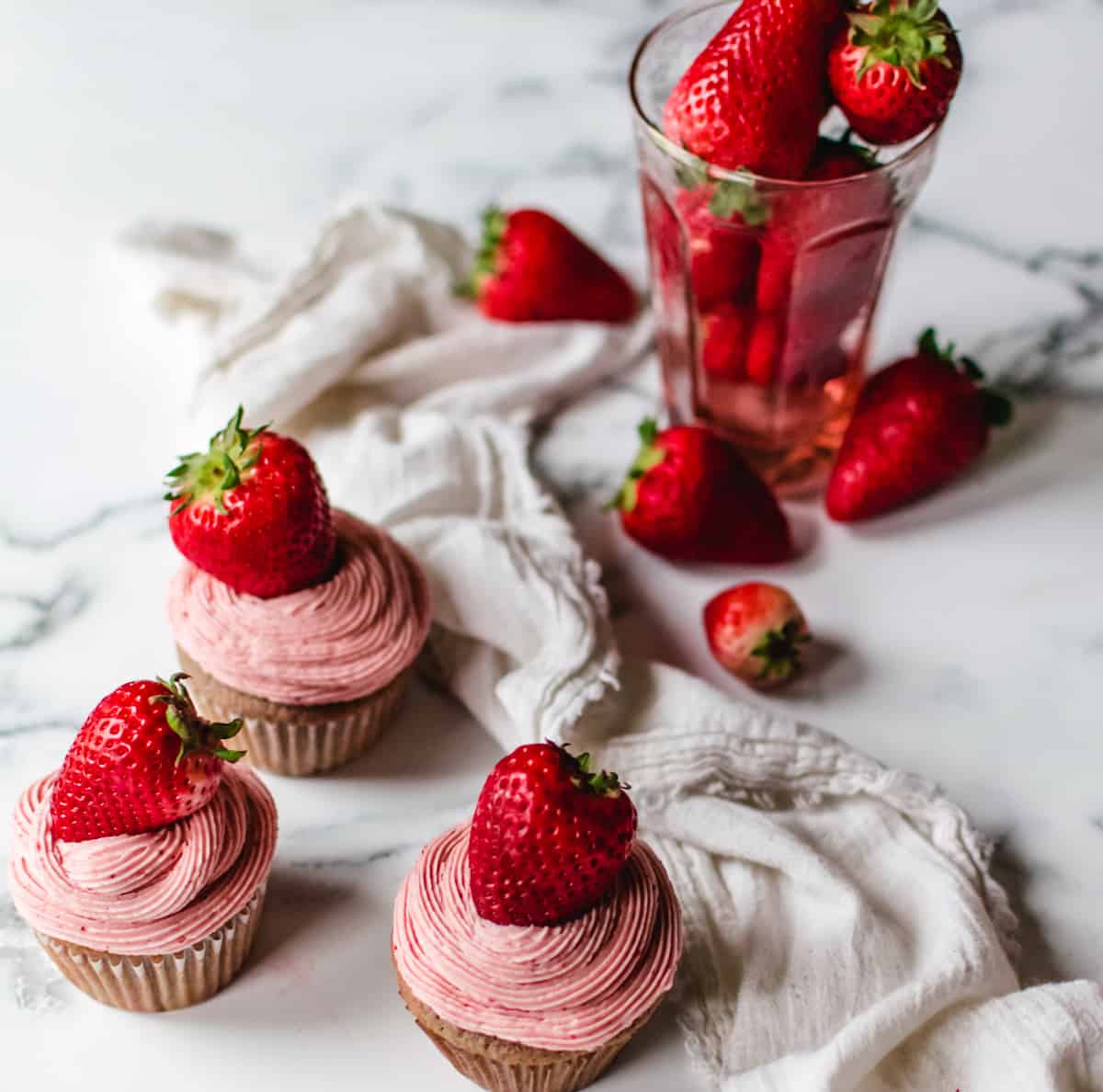 pink strawberry flavored cupcakes topped with a fresh strawberry