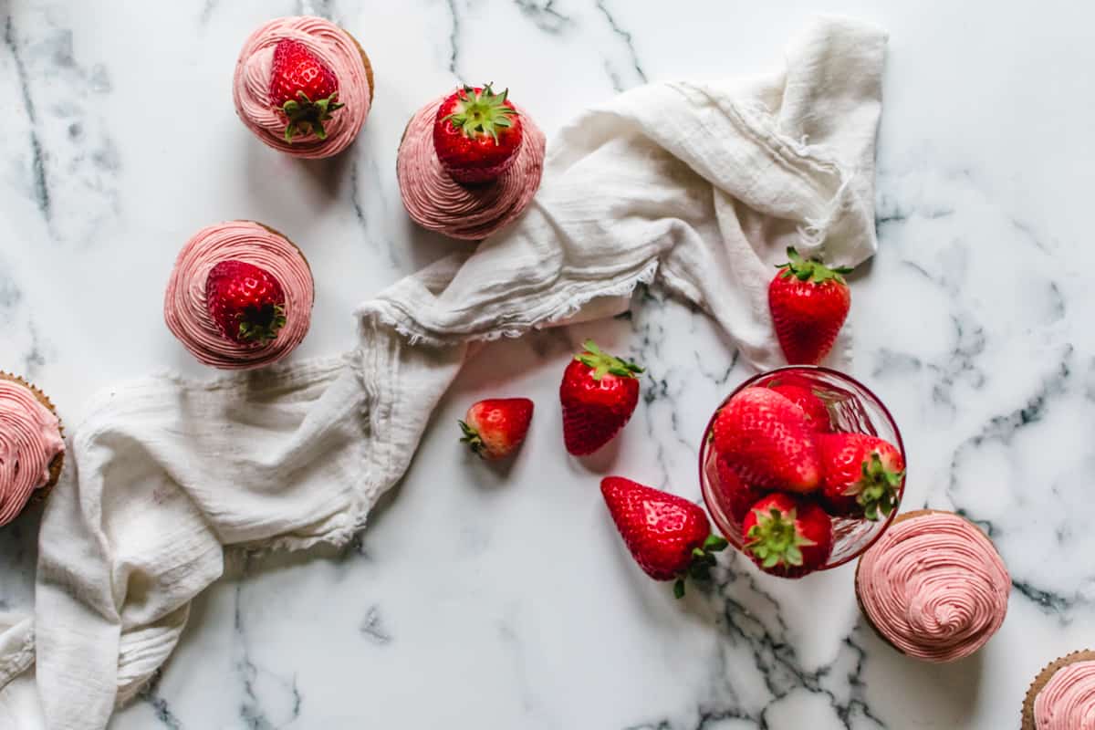 strawberry cupcakes with pink frosting topped with fresh strawberry