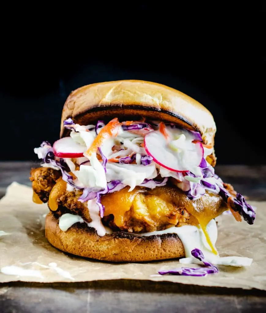 crispy fried chicken topped with cheese and carrot radish slaw on brioche hamburger bun